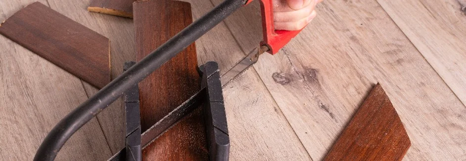 Person sägt Holzbrett mit Bügelsäge